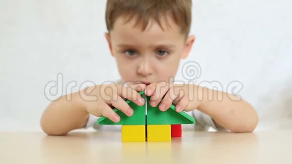 一个孩子正在玩彩色积木盖房子坐在白色背景的桌子旁特写镜头视频的预览图