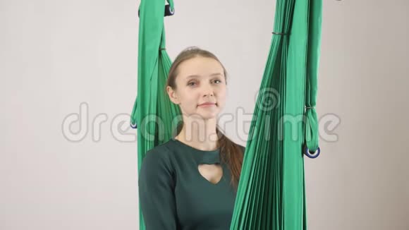 年轻的女人坐在吊床上精疲力竭倒在吊床上空中航空飞行健身教练训练冥想视频的预览图