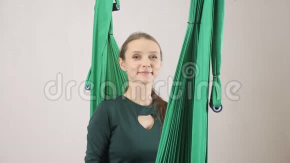 年轻女子坐在吊床上微笑着伸出双手大声喊叫空中航空飞行健身教练训练冥想视频的预览图