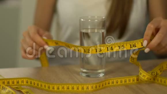女人用胶带线测量一杯水痴迷于卡路里厌食症视频的预览图