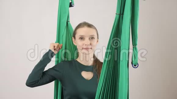 年轻的女人坐在吊床上微笑的女人得到了一个想法并伸出手指空中航空飞行健身教练训练视频的预览图