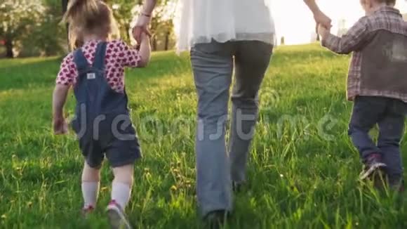 日落时分母亲和孩子们手拉手一起在草地上奔跑视频的预览图