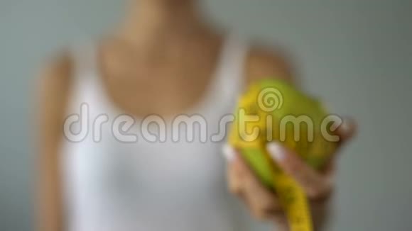 女孩拿着苹果裹着测量胶带计算卡路里节食视频的预览图