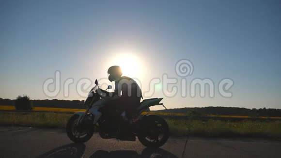 戴头盔的人骑着摩托车在高速公路上背景是太阳耀斑驾驶摩托车的摩托车视频的预览图