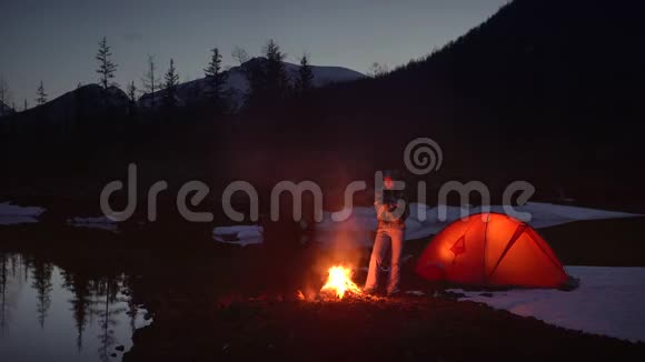 晚上在山上露营的火堆里女人温暖了双手视频的预览图