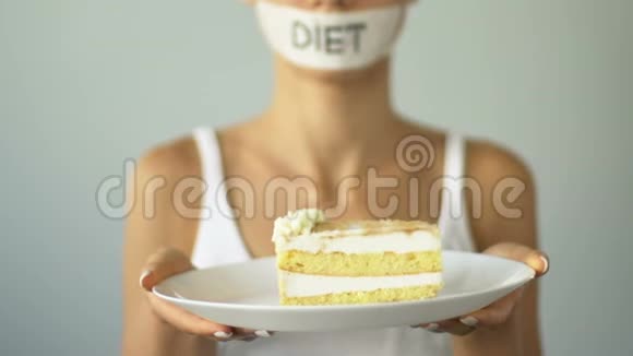 节食的女孩拿着蛋糕诱惑渴望苗条高热量的食物视频的预览图