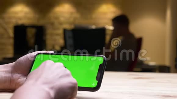 办公室室内绿色彩色屏幕的女性手在手机上播放视频的特写后景拍摄视频的预览图