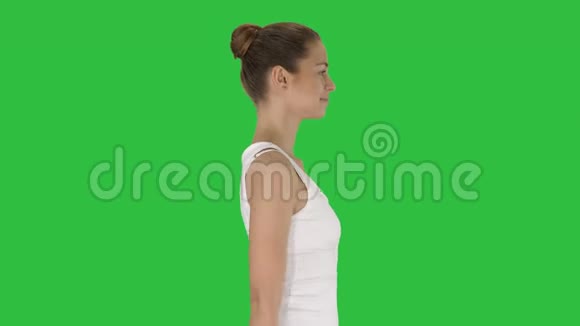 穿白色上衣的休闲年轻女子在绿色屏幕上行走Chroma键视频的预览图