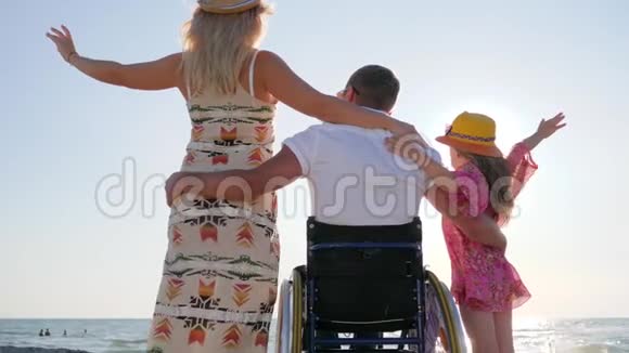 残疾拥抱妻子和女儿在背景海上与孕妇和孩子无效家庭幸福视频的预览图