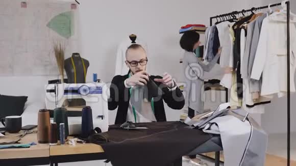 裁缝或时装设计师坐在工作室的工作场所用大剪刀裁剪灰色织物在里面视频的预览图