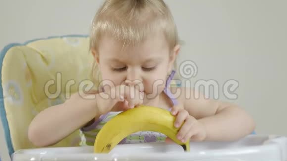 坐在婴儿椅上吃香蕉的小女孩视频的预览图