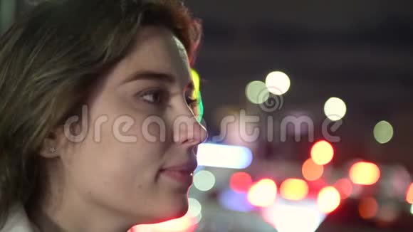 美丽的女人在夜城看着摄像机想着视频的预览图