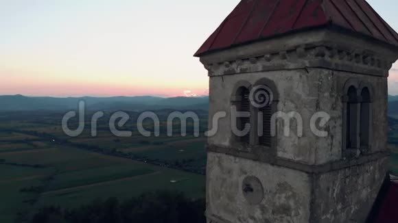 日落时分一座古老的天主教教堂在山上的空中近景拍摄在夏天的时候可以看到村庄的美丽景色视频的预览图