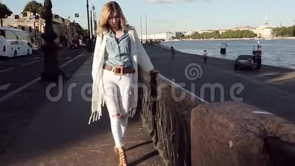 一个穿牛仔裤和白色羊毛衫的时髦女人的肖像视频的预览图