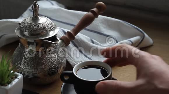 一个男人用双手把咖啡从水壶里倒入一个小杯子里喝咖啡视频的预览图