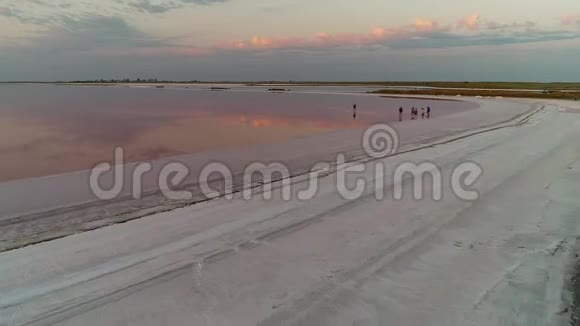 在游客行走的河口上空的粉红色云层视频的预览图