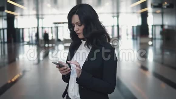 穿着西装的女孩正在智能手机上输入一条信息办公室大厅里女商人的画像视频的预览图