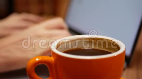 女人在笔记本电脑上工作桌子上放着一杯咖啡远处的咖啡馆工作自由职业概念4k视频的预览图