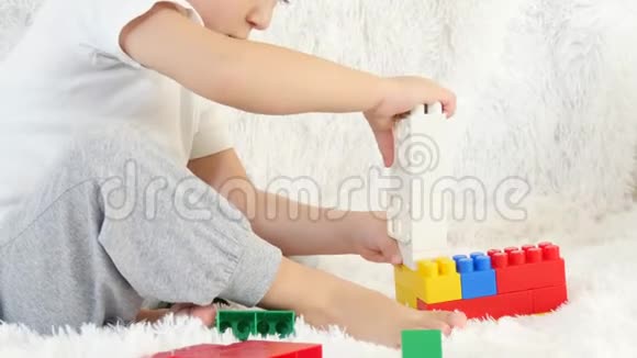 小男孩在彩色积木里玩耍坐在白色的背景上孩子和玩具运动相机滑块视频的预览图