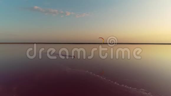 夕阳落在一个粉红色的湖上一个放风筝的人沿着一个平静的湖狂奔视频的预览图