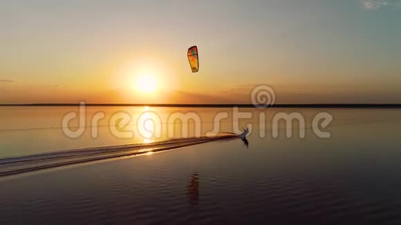 空中射击一个风筝手的轮廓控制着一个橙色的训练风筝在湖中央视频的预览图
