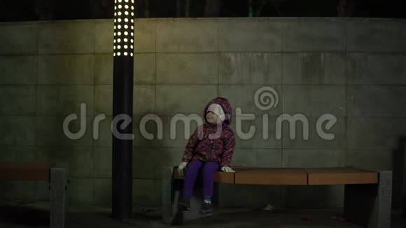 晚上在公园里孩子在灯笼的灯光下坐在长凳上视频的预览图