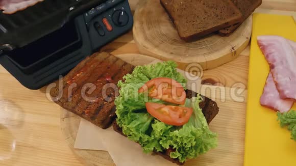 在厨房里做三明治手上的火钳从烤架上取出一块刚烤好的热肉视频的预览图