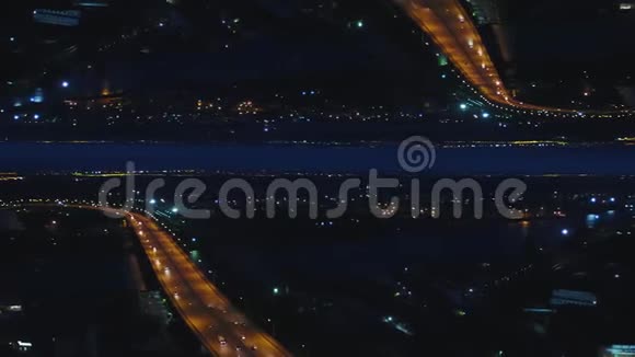空中夜景的河桥有移动的汽车和城市有夜间灯光镜面地平线效果媒体视频的预览图