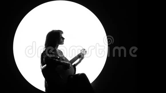 一个黑色和白色的视频片段一个美丽的女孩在古典吉他上演奏在烟雾中的白色圆圈视频的预览图