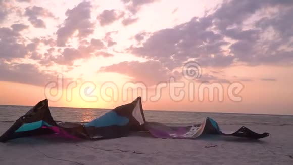 一只紫色的大型训练风筝躺在海滩上视频的预览图