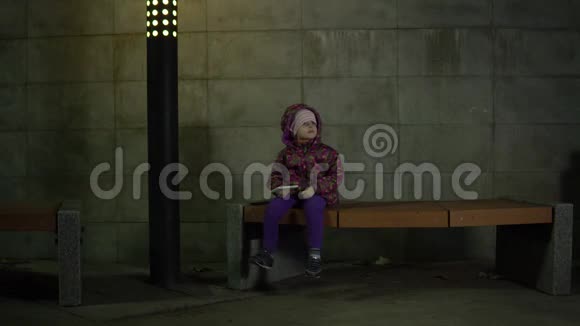 晚上在公园里孩子在灯笼的灯光下坐在长凳上视频的预览图