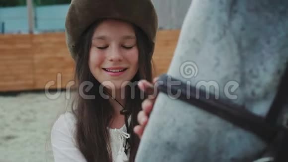 一个快乐的女孩在这个地区对她友好的白马微笑的肖像4K视频的预览图