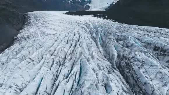 黑色火山灰和湖泊的白色冰川山脊的空中俯视图视频的预览图