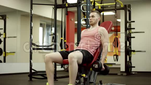 男人举起哑铃在健身房锻炼二头肌视频的预览图
