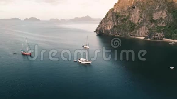 空中无人机拍摄的高山覆盖热带森林和船只锚定在海湾热带景观视频的预览图