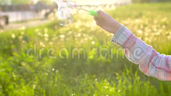 女孩子手吹在公园玩肥皂泡例如人们在夏天的晴天在外面玩视频的预览图