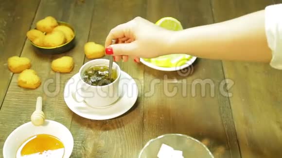 一个女人把刚泡好的绿茶和勺子放在杯子里视频的预览图