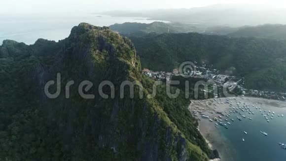 空中无人机拍摄的高山覆盖热带森林和船只锚定在海湾热带景观视频的预览图