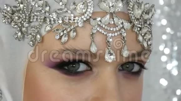 模特的脸是白色的银质的皇冠上有一个明亮的多色妆叫做烟熏眼摆在前面视频的预览图
