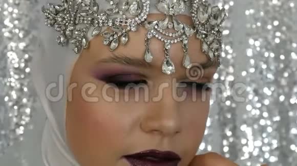 模特的脸是白色的银质的皇冠上有一个明亮的多色妆叫做烟熏眼摆在前面视频的预览图
