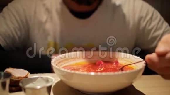 一个留胡子的男人在吃加了酸奶油的罗宋汤红甜菜汤波什视频的预览图