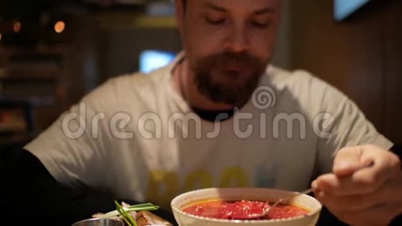 一个留胡子的男人在吃加了酸奶油的罗宋汤红甜菜汤波什视频的预览图