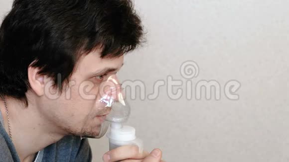 使用雾化器和吸入器进行治疗年轻人通过吸入面罩和咳嗽吸入侧视视频的预览图