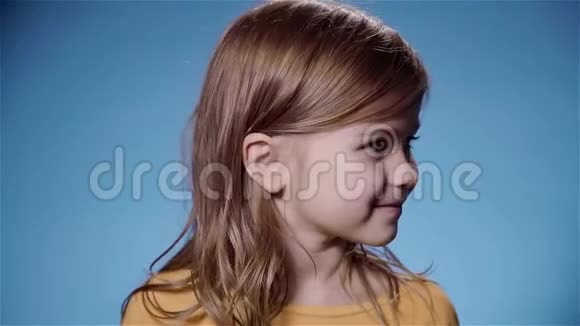 可爱的小女孩美丽的头发微笑蓝色背景慢动作视频的预览图