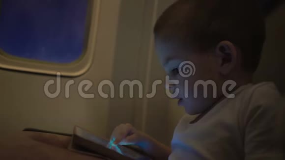 可爱的男孩坐飞机玩电脑平板电脑视频的预览图