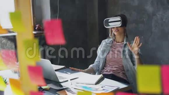 迷人的年轻女子坐在桌子旁戴着虚拟现实眼镜她动了手还有VR视频的预览图