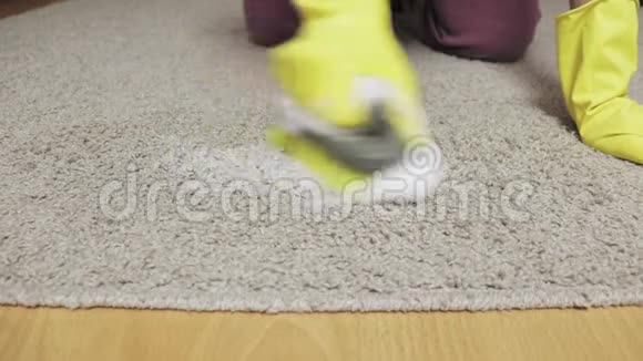 戴黄色橡胶手套的女人用刷子和泡沫清洗地毯视频的预览图