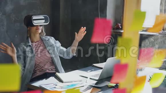 迷人的年轻女子坐在桌子旁戴着虚拟现实眼镜她动了手还有VR视频的预览图