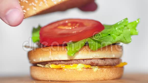 男性手在多汁美味的汉堡特写镜头上放上芝麻面包视频的预览图