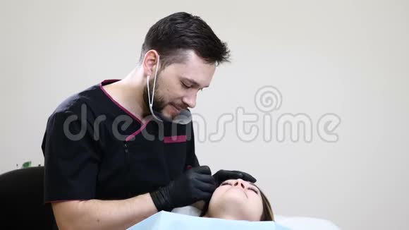 戴黑色手套的男性美容师在女性眉毛上做永久化妆的画像视频的预览图